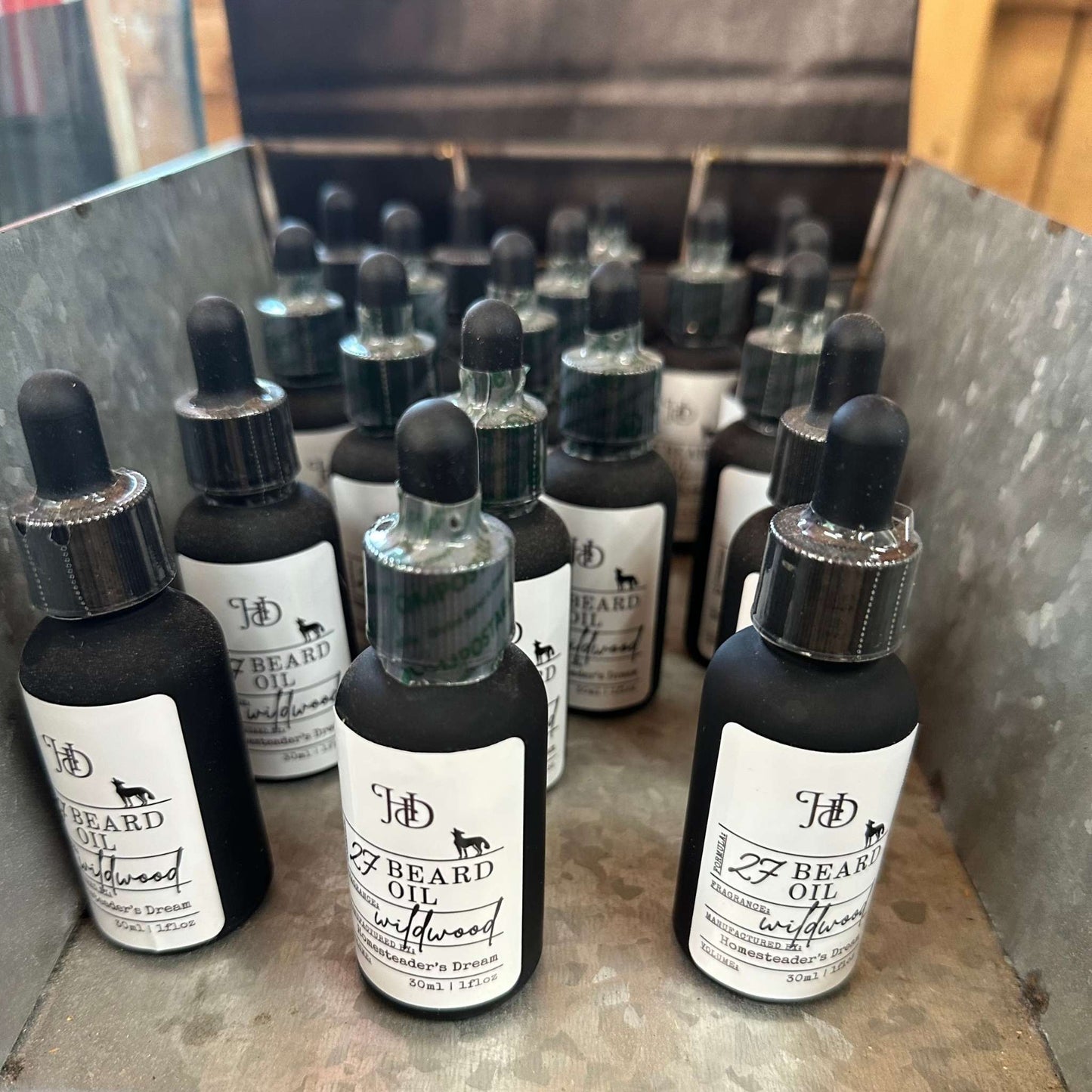 Bottles of Wildwood Beard Oil on a metal surface with a wooden background.