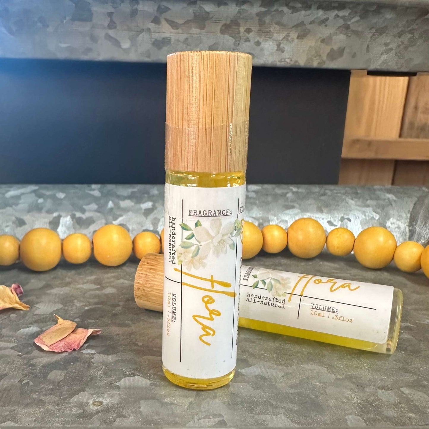 Flora jasmine perfume roll-on bottle with wooden cap on a metal tray with yellow beads