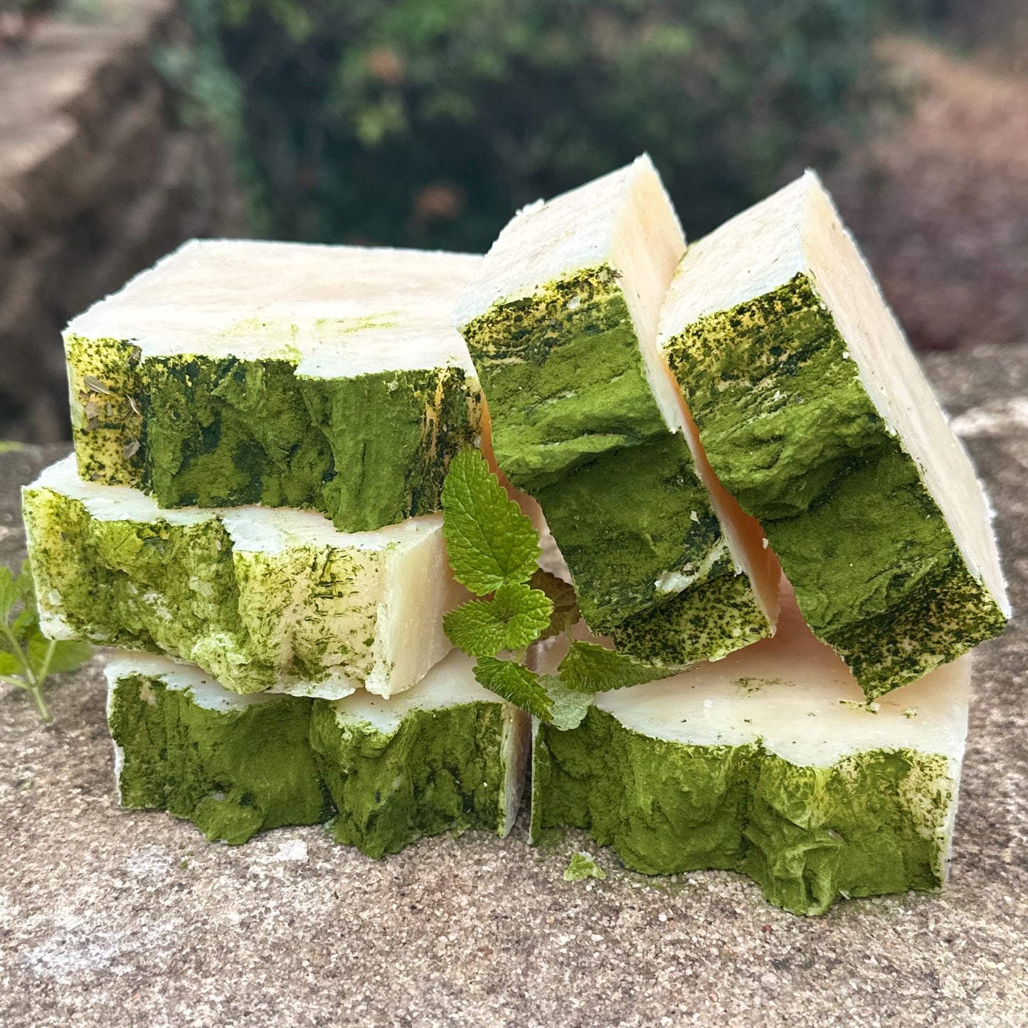 Green and white layered soap bars on a stone surface