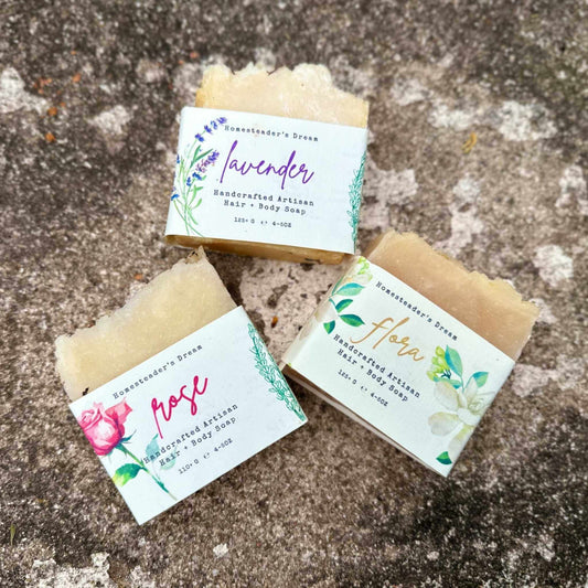 Three bars of floral soap with linen labels on a stone surface