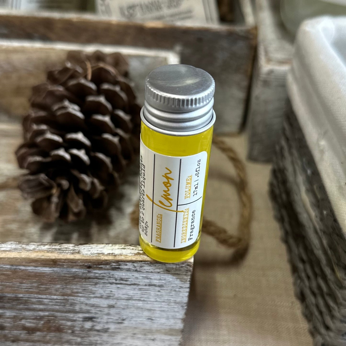 organically crafted lemon fragrance vial, closeup on wooden crate with pinecone decor