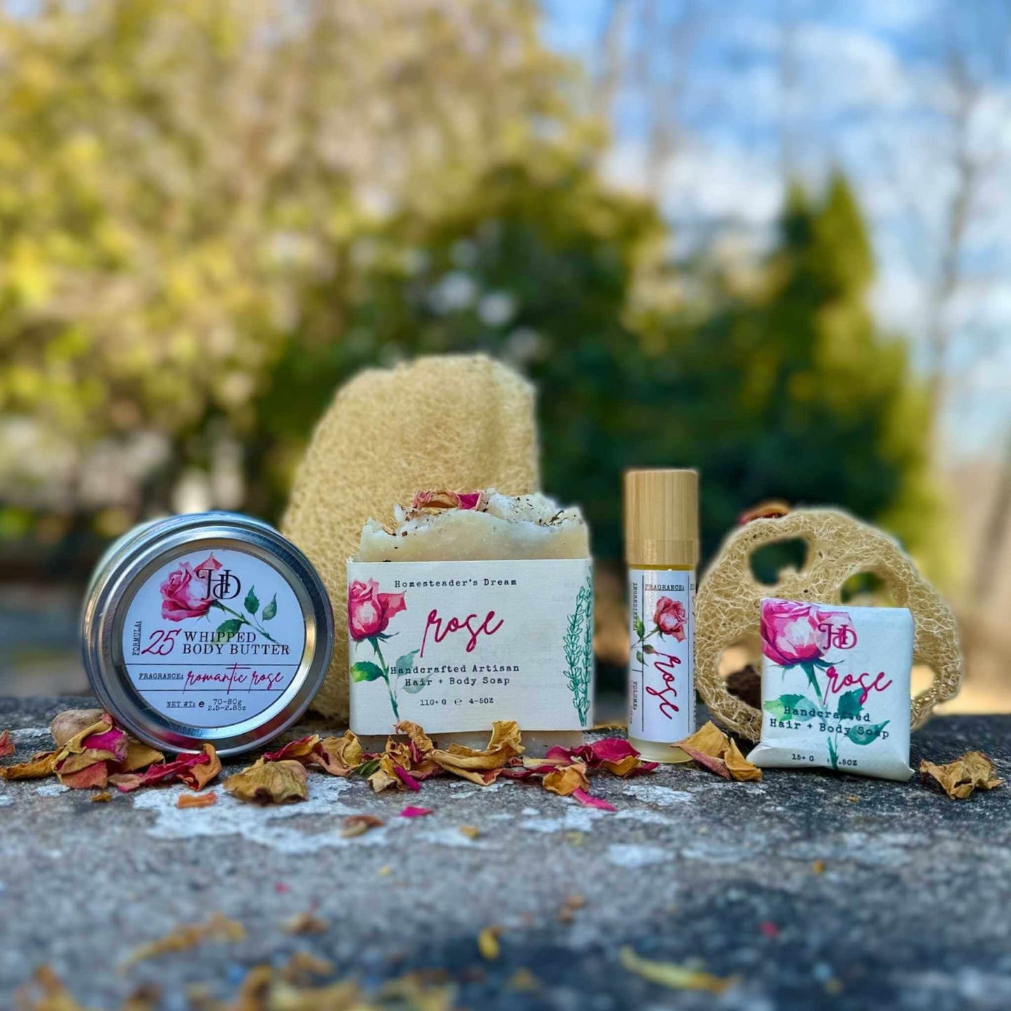 Collection of natural skincare products with floral design labels on a stone surface outdoors.