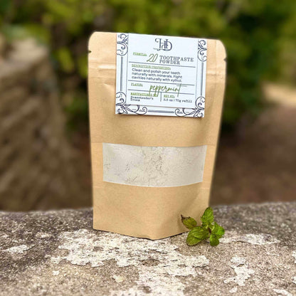 Kraft paper packaging of toothpaste powder with a label on a stone surface.