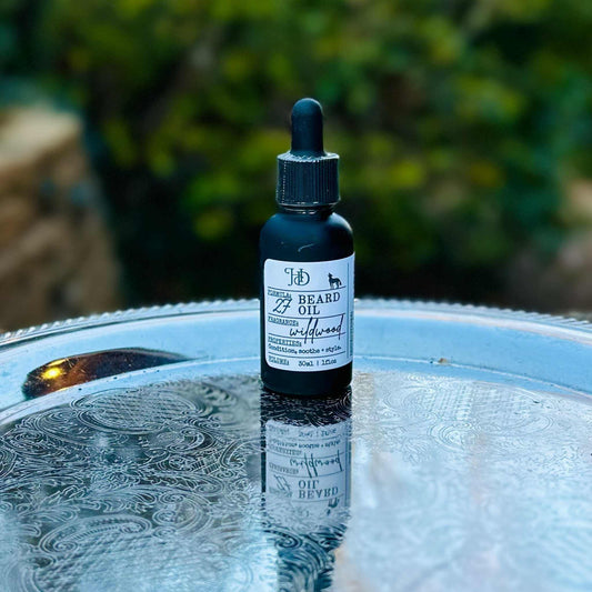 Bottle of beard oil on a reflective surface with a blurred natural background