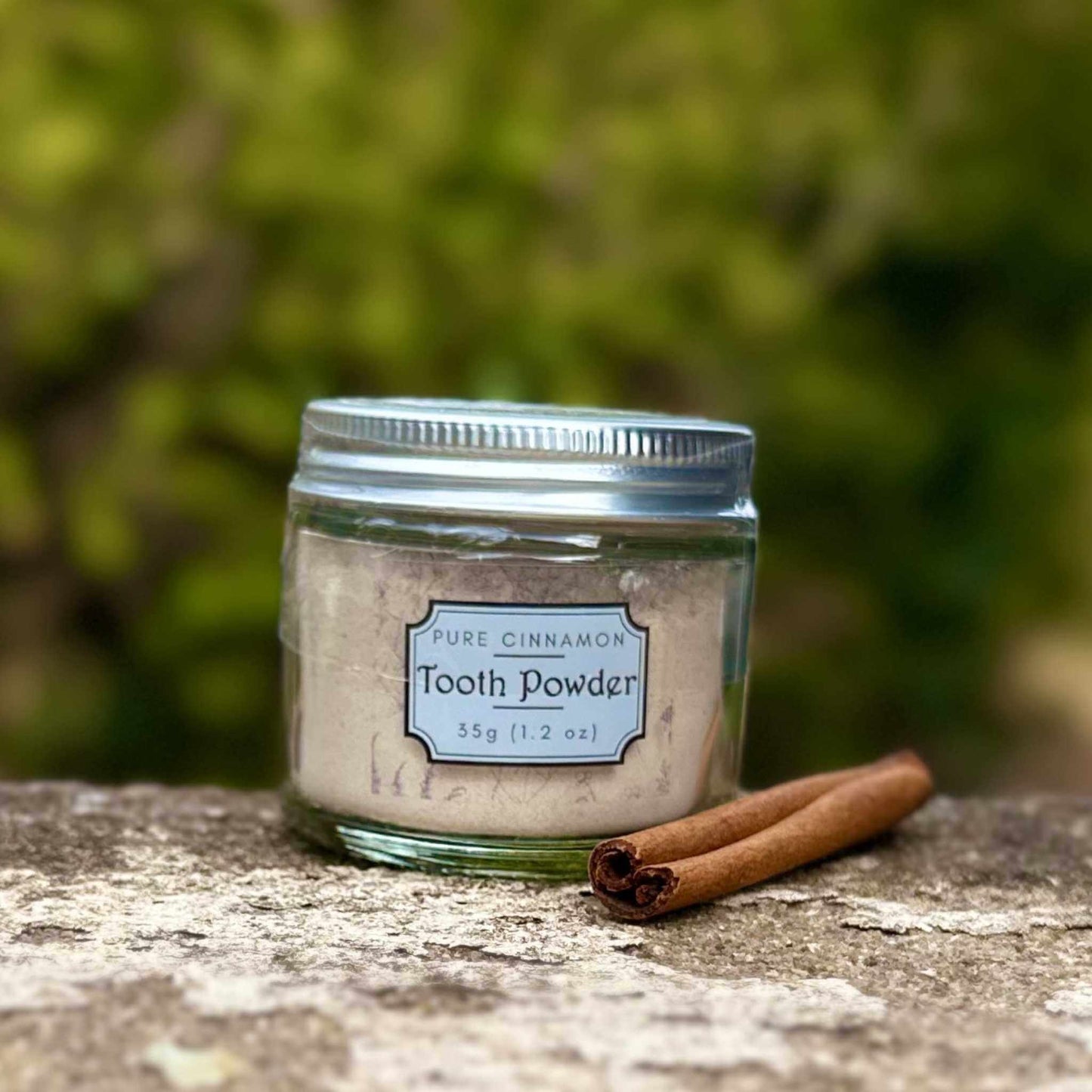Jar of tooth powder with a cinnamon stick on a natural surface