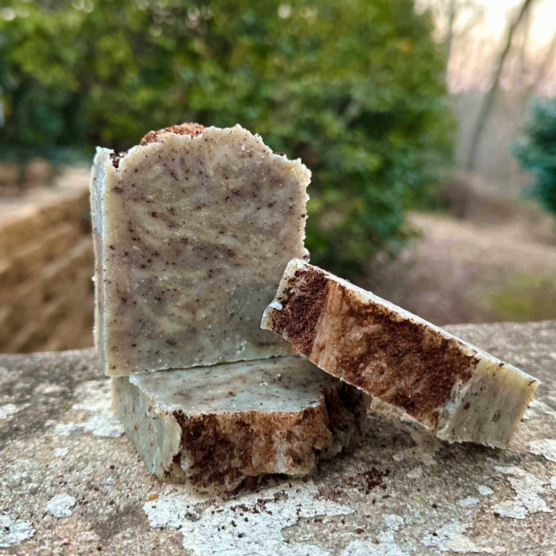 Two pieces of soap on a stone surface with a natural background