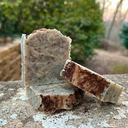 Two pieces of soap on a stone surface with a natural background