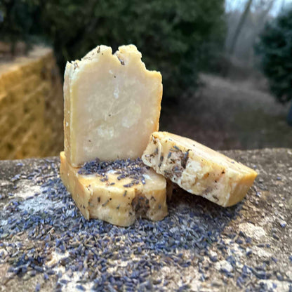 Three soap bars with visible textures on a textured surface outdoors.