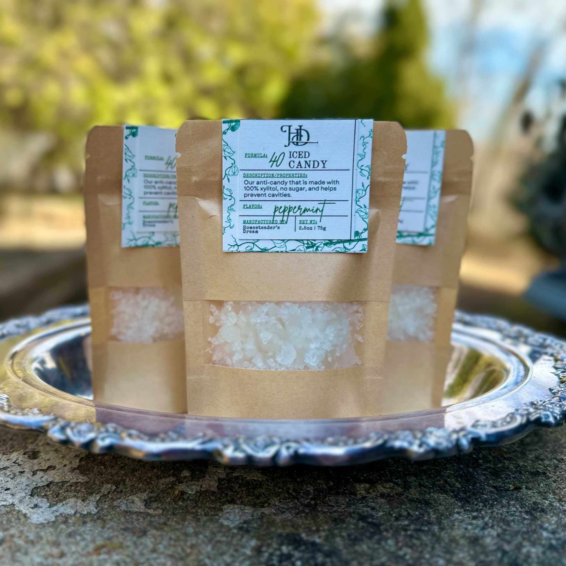 Two packages of iced candy on a decorative silver platter with a blurred natural background
