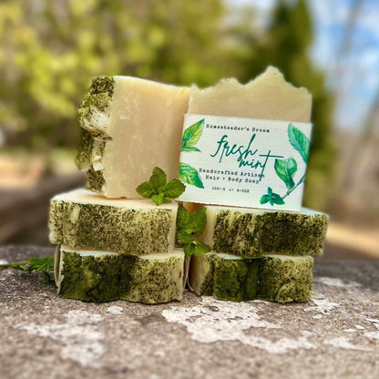 Stack of soap bars with a 'fresh mint' label on a natural surface.