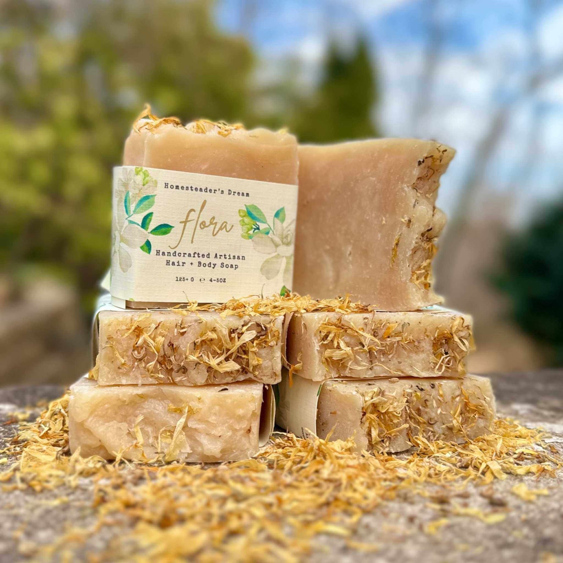 Stack of handmade soap bars with a 'flora' label against a natural background