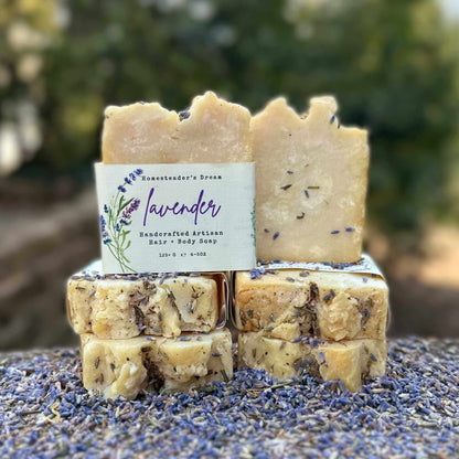 Stack of lavender soap bars with a visible label on a surface with lavender flowers.