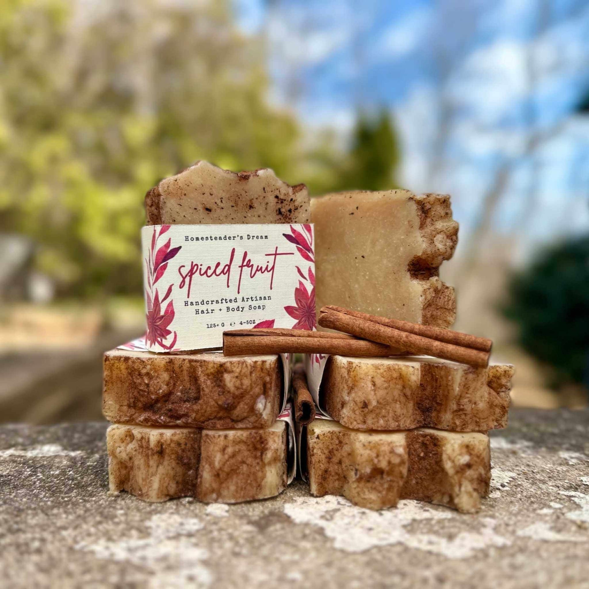 Stack of handmade soap bars with a 'Spiced Fruit' label against a blurred natural background