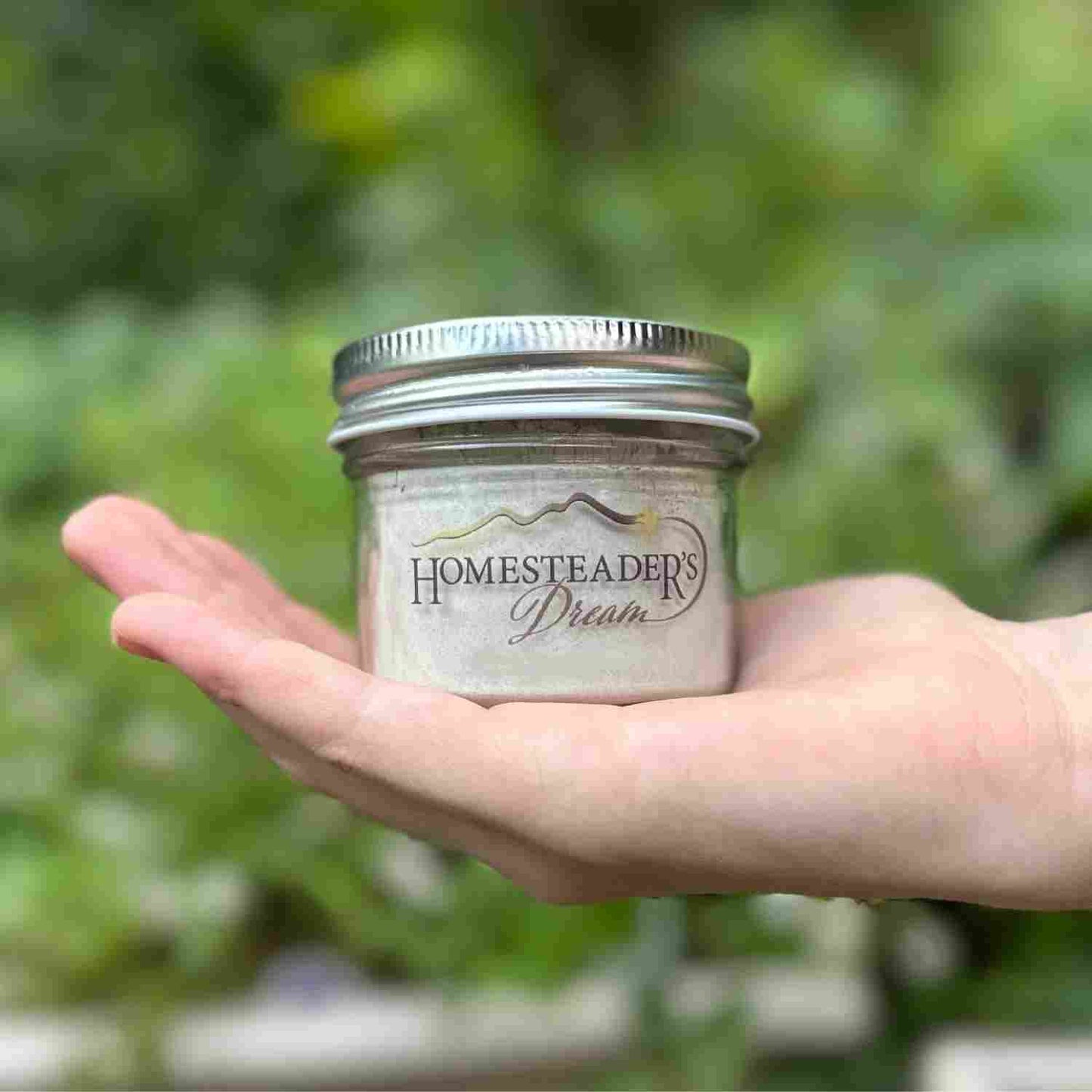 Hand Holding Large Tooth Powder Jar with Homesteader's Dream Logo
