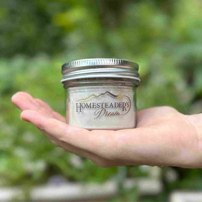 Hand Holding Large Tooth Powder Jar with Homesteader's Dream Logo