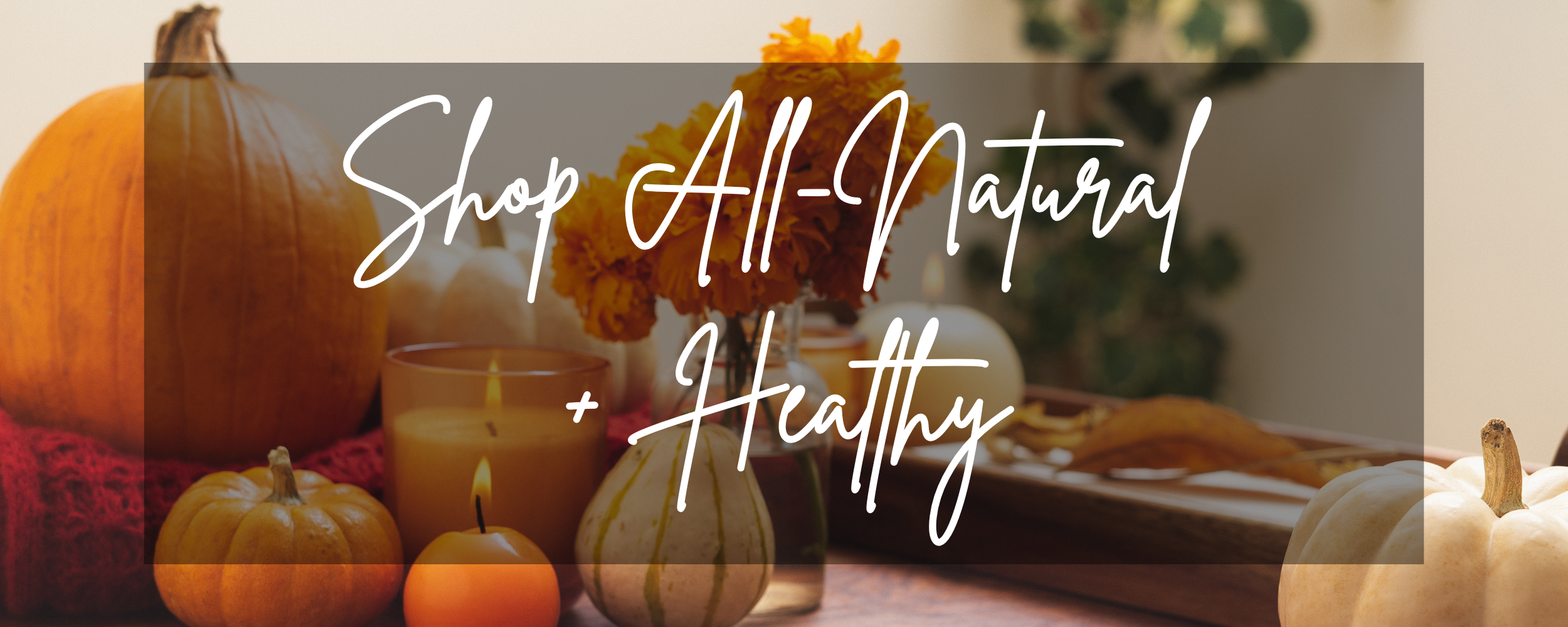 Decorative banner with pumpkins, candles, and text 'Shop All-Natural + Healthy' on a blurred background.