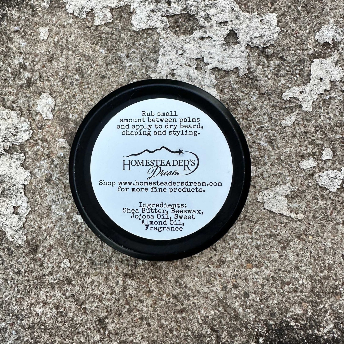 Tin base with 'Homesteaders Dream' branding and product information on a textured surface.