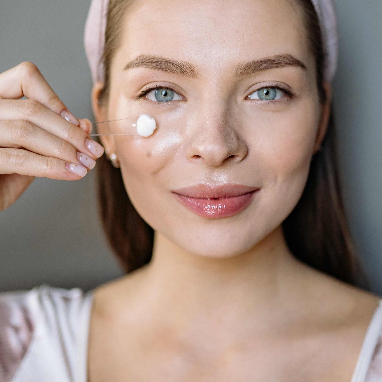 Woman applying body butter to her face with a small spatula.