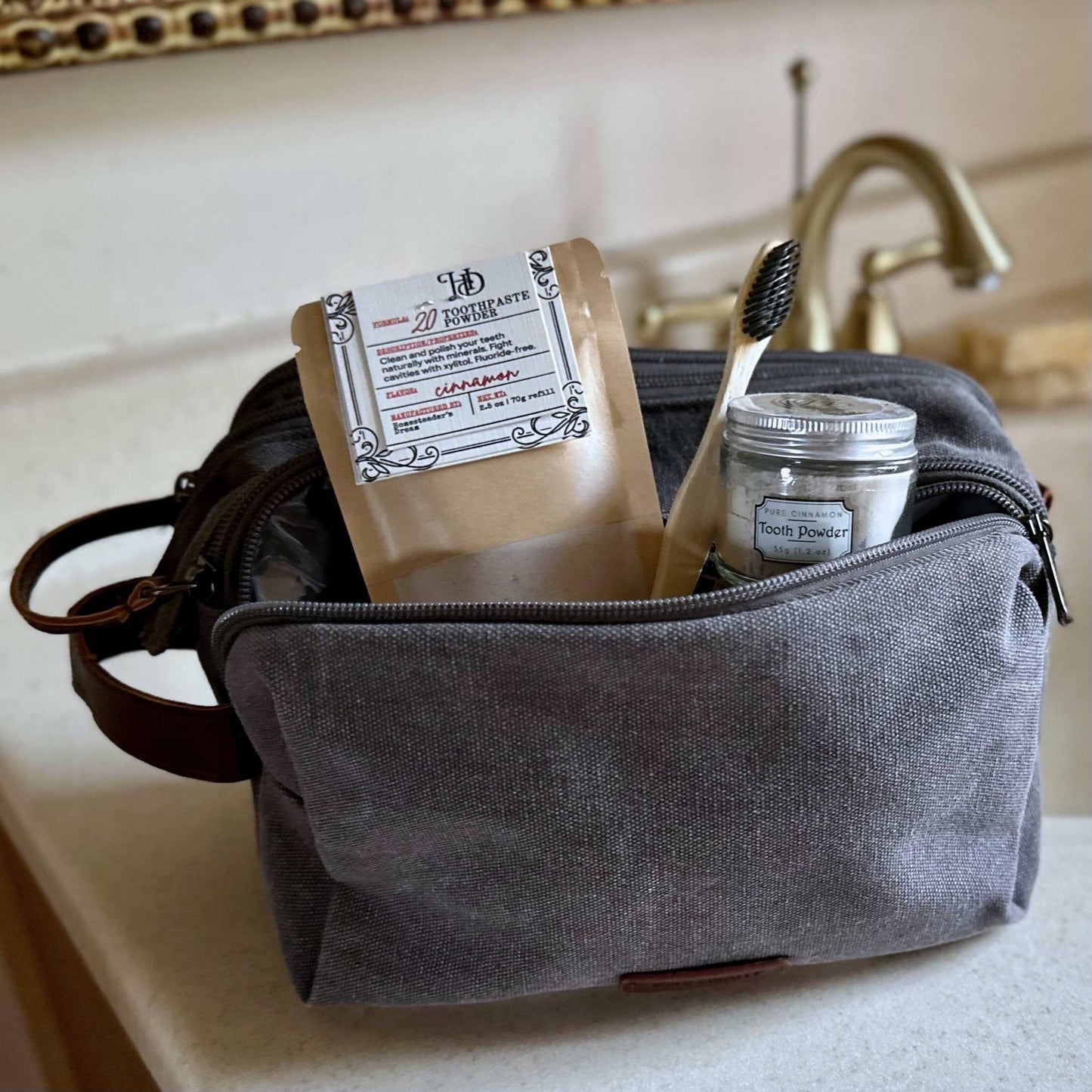 Gray toiletry bag with toothpaste and dental items on a bathroom counter