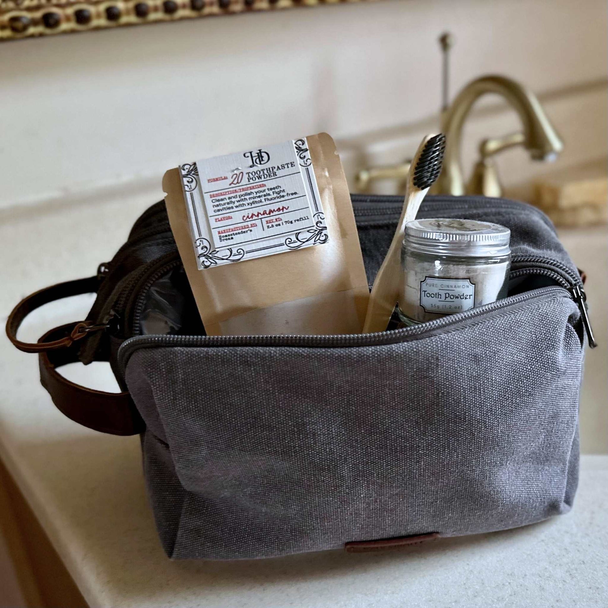 Gray toiletry bag with toothpaste and dental items on a bathroom counter
