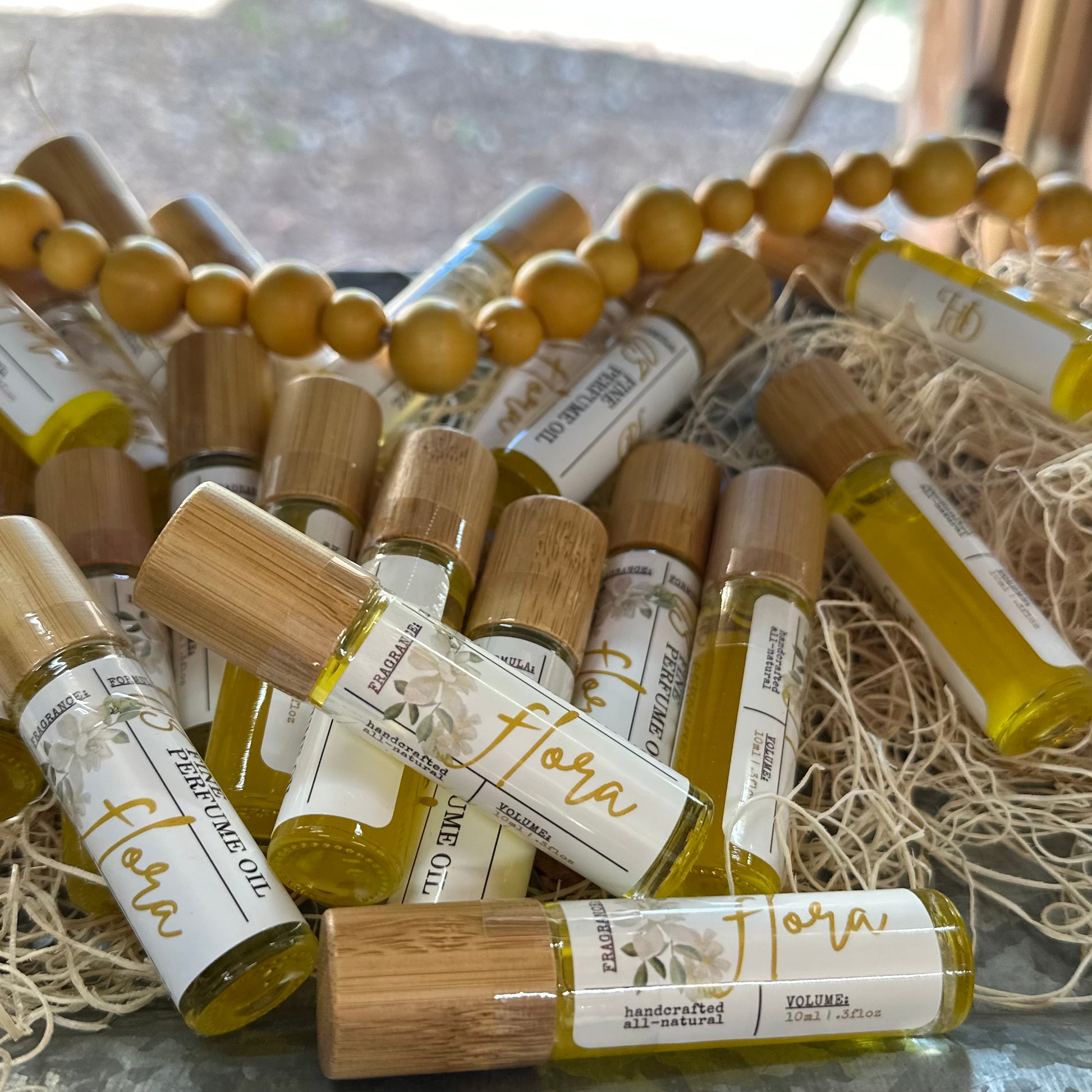 Collection of small bottles labeled 'Flora' on a textured surface with beads and straw.