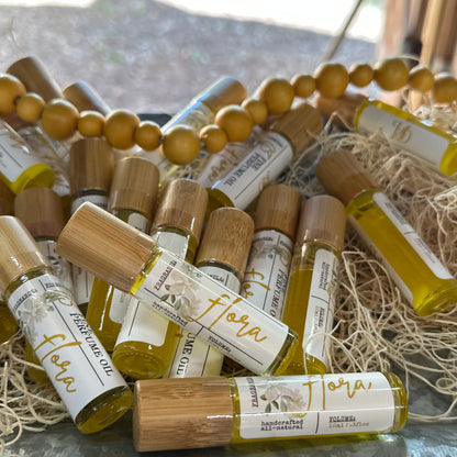 Collection of small bottles labeled 'Flora' on a textured surface with beads and straw.