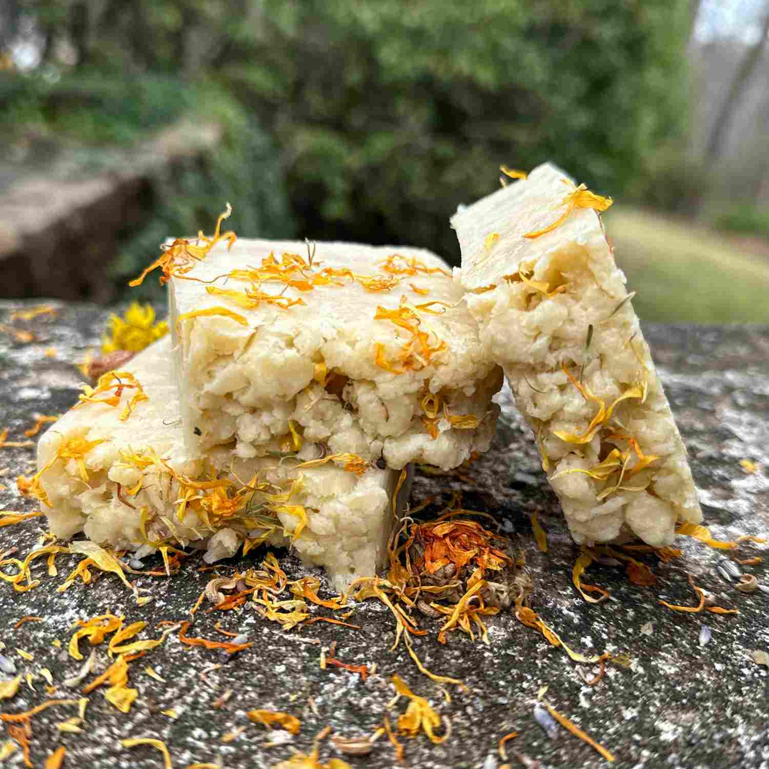 trio of jasmine flora soaps on a stone bench with calendula sprinkled around