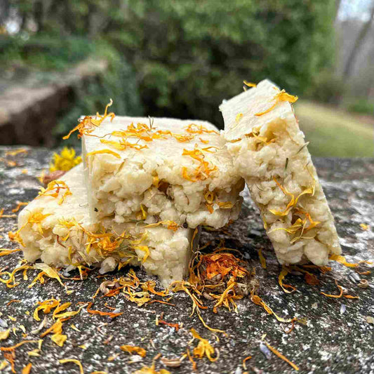 trio of jasmine flora soaps on a stone bench with calendula sprinkled around
