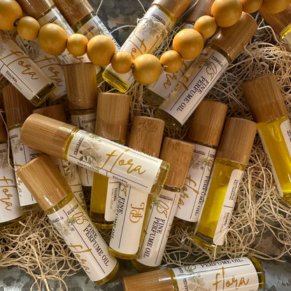 Collection of Flora perfume oil bottles with bamboo caps on a rustic surface.