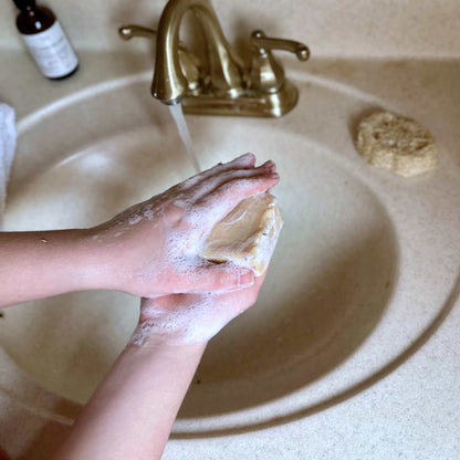Person washing hands with soap under running water in a sink.