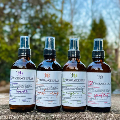 Four fragrance spray bottles with labels on a natural background