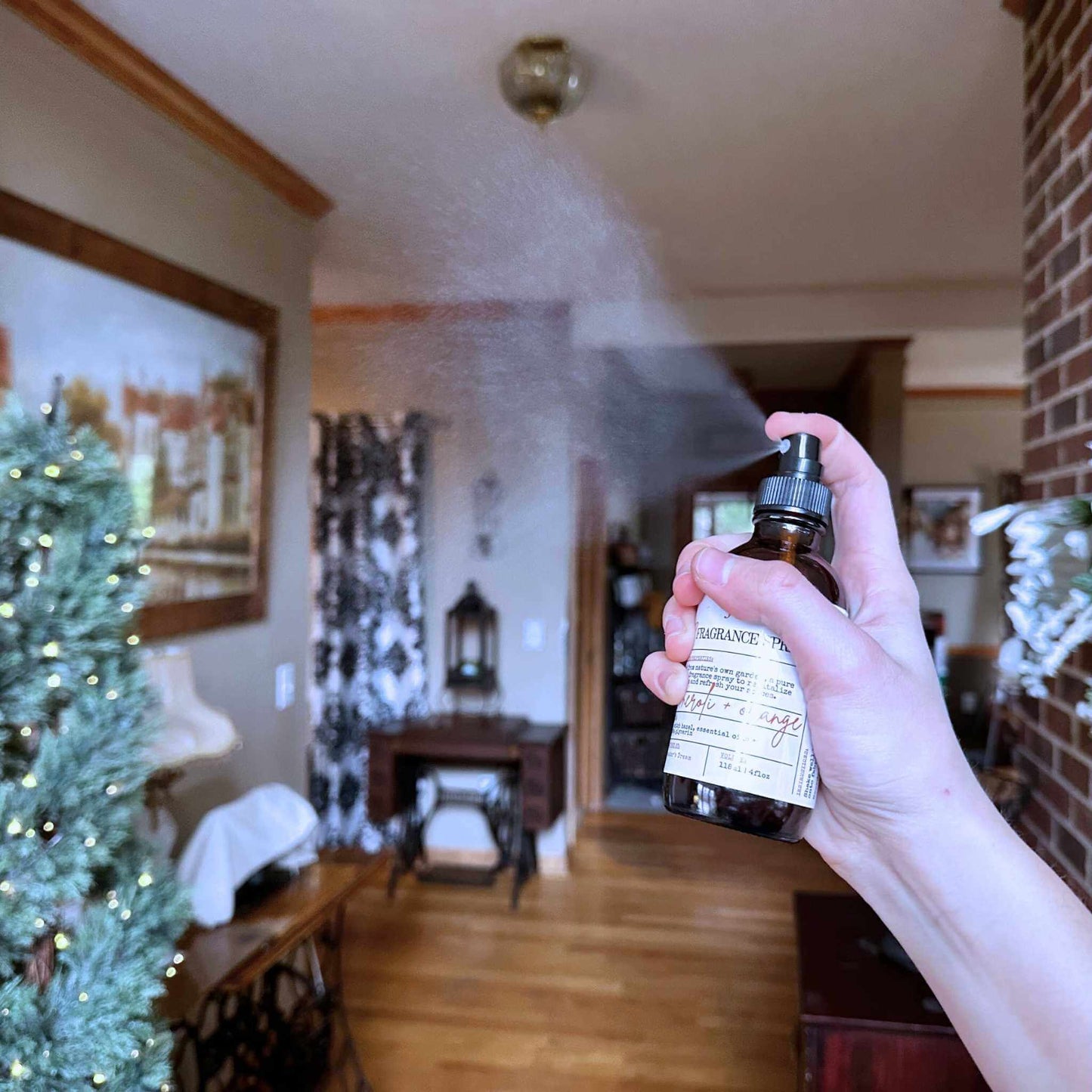 Hand holding a bottle of fragrance spray misting an elegant room.