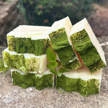 Green and white layered soap bars on a stone surface