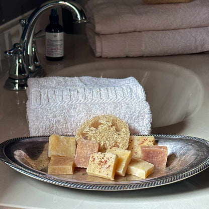 Assorted guest soaps on a silver tray with a towel and sink in the background