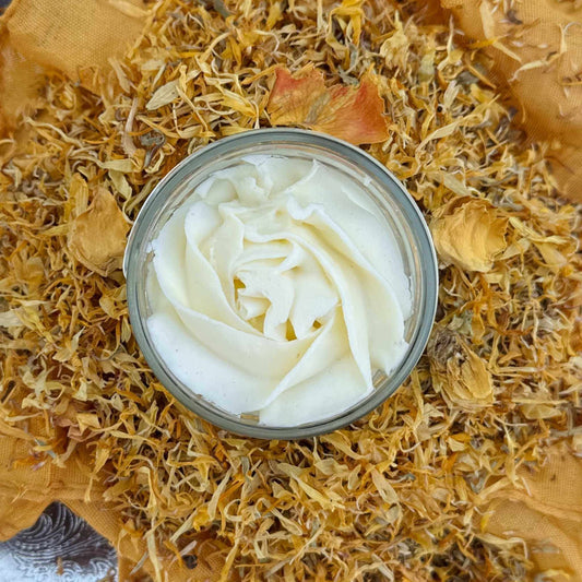 Jar of white jasmine body butter surrounded by dried flowers and leaves
