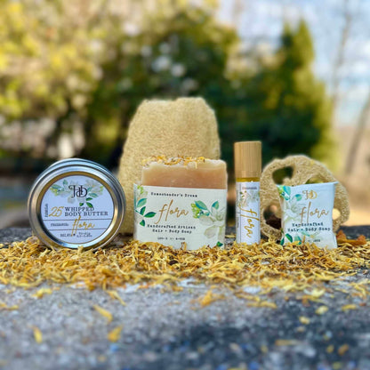 Collection of jasmine natural skincare products with 'Flora' branding outdoors.