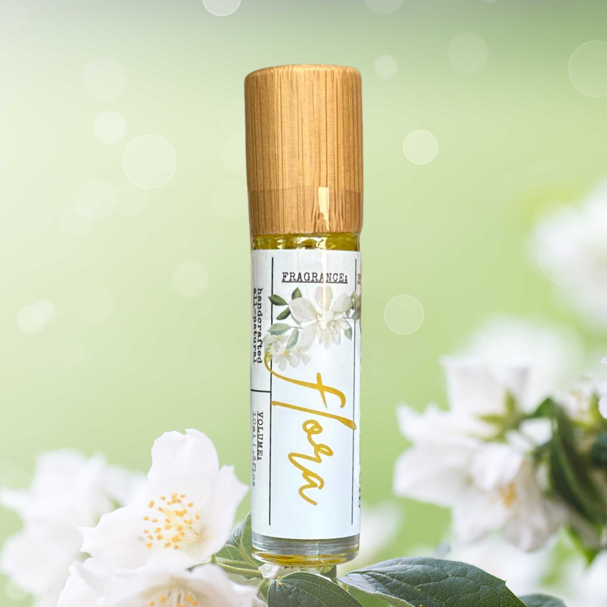 Roll-on perfume bottle with wooden cap and floral label against a green background with flowers.