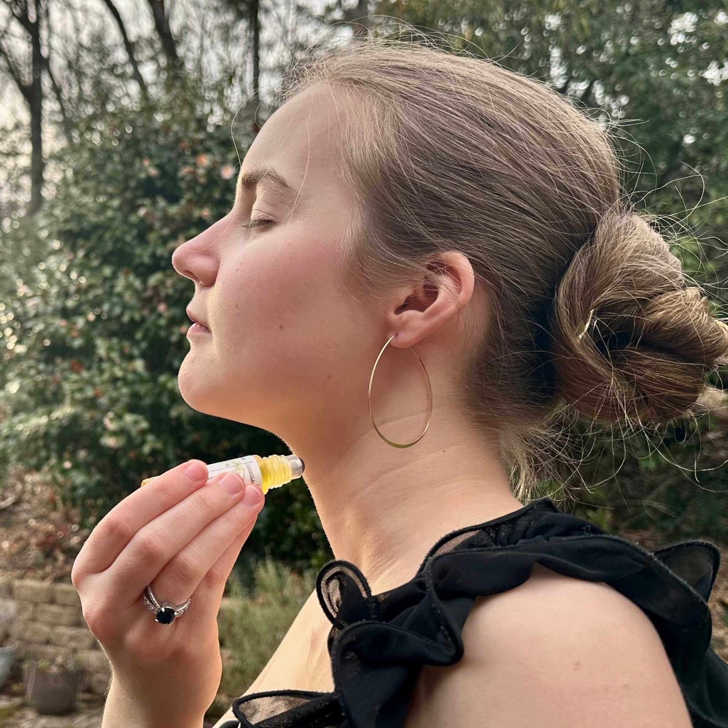 Woman outdoors applying jasmine perfume