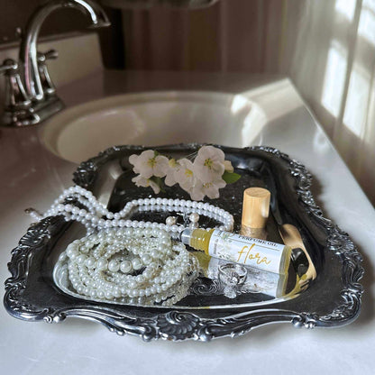 Silver tray with pearls, jasmine flowers, and a perfume bottle on a bathroom counter