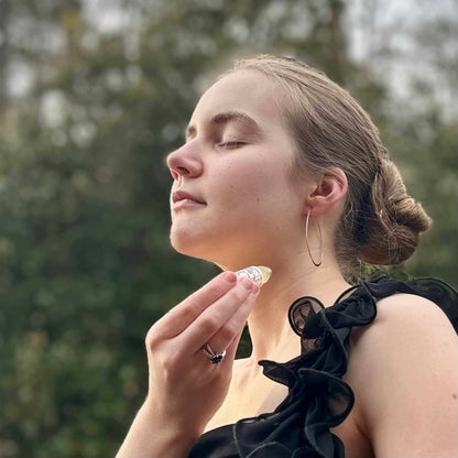 Woman holding perfume outdoors with trees in the background