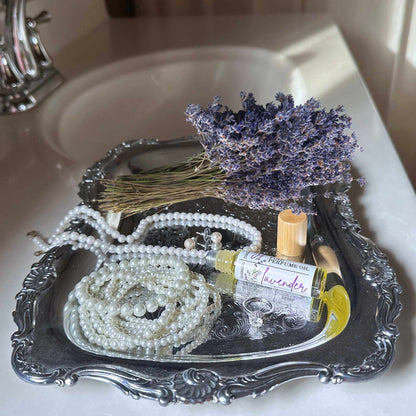 Tray with dried lavender, pearls, and a bottle of lavender perfume on a sink.