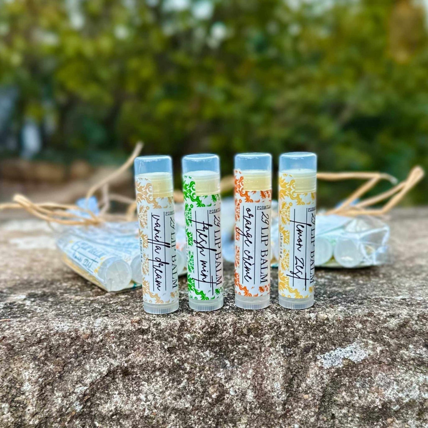 Four lip balms with HD branding on a stone surface with a blurred natural background