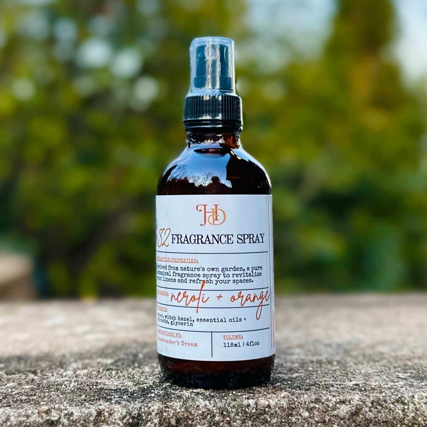 Fragrance spray bottle with label on a stone surface with a blurred green background