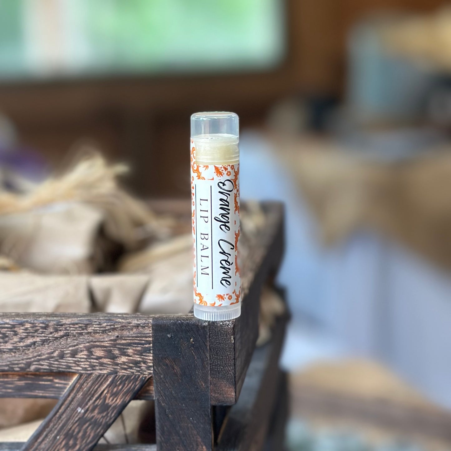 orange creme lip balm on wooden crate with blurred background