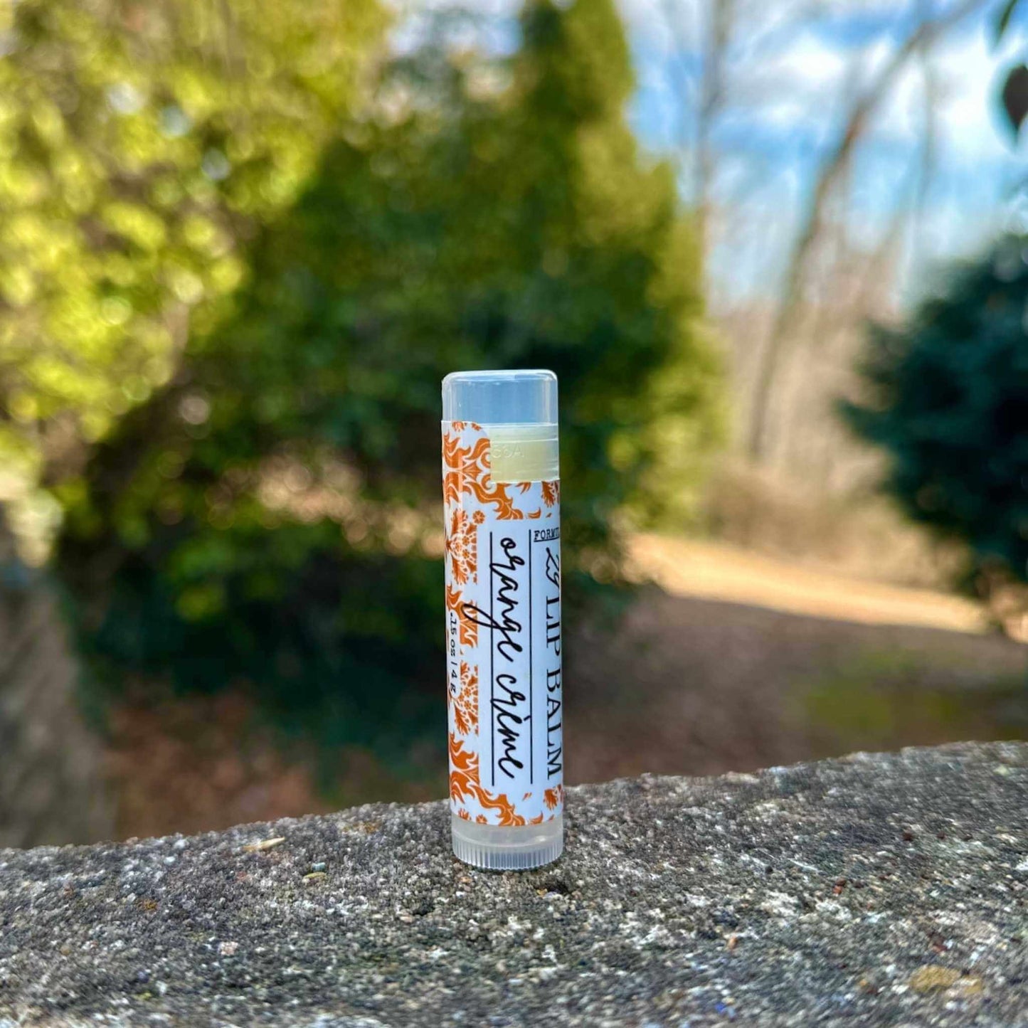 Lip balm tube with floral design on a stone surface with a natural background