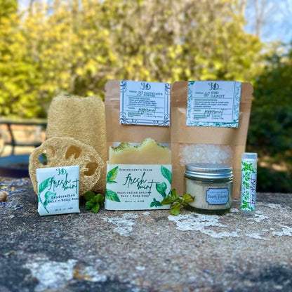 Collection of peppermint natural products including soap, candy, and other items on a stone surface with greenery in the background.