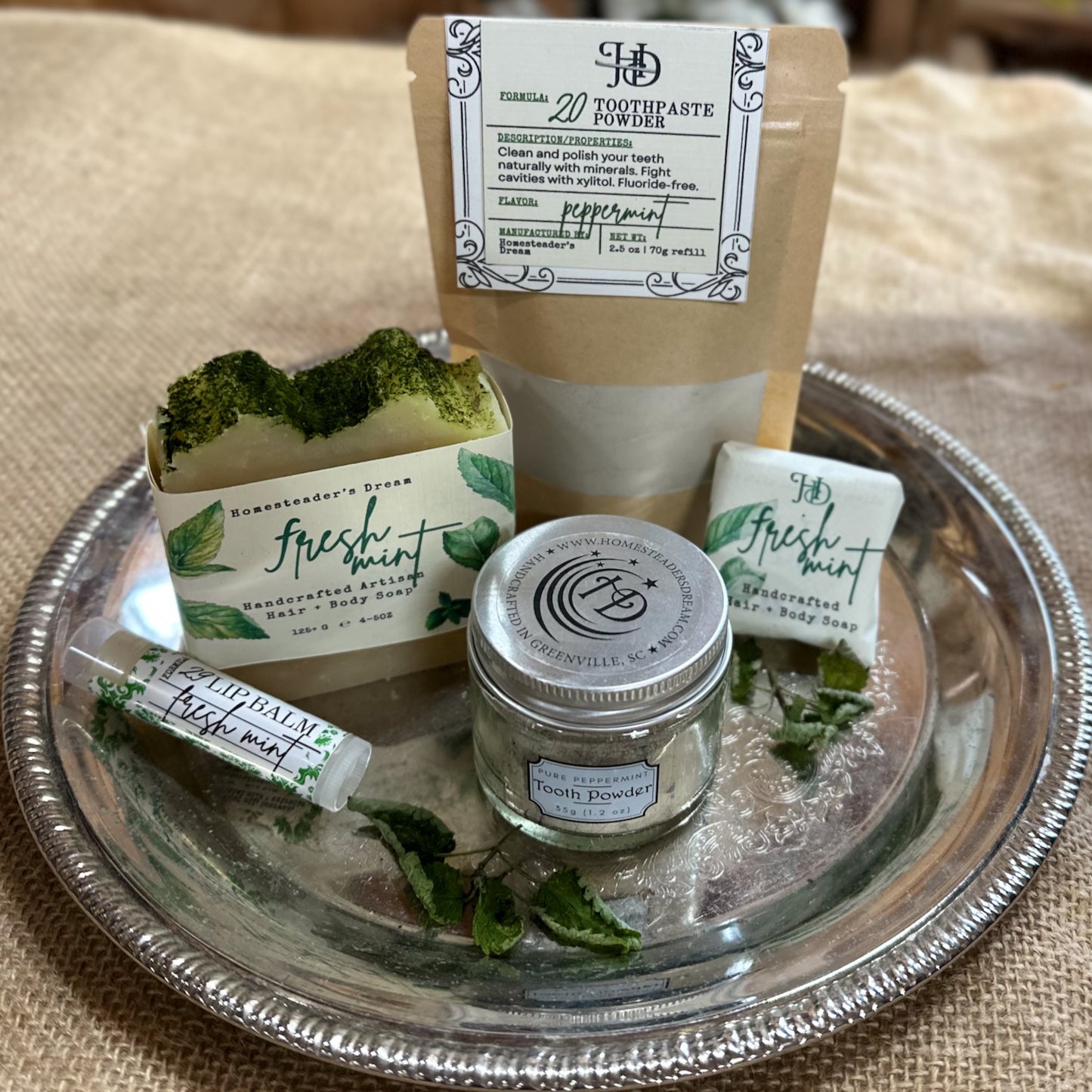 Collection of natural dental care products on a silver tray with a beige background