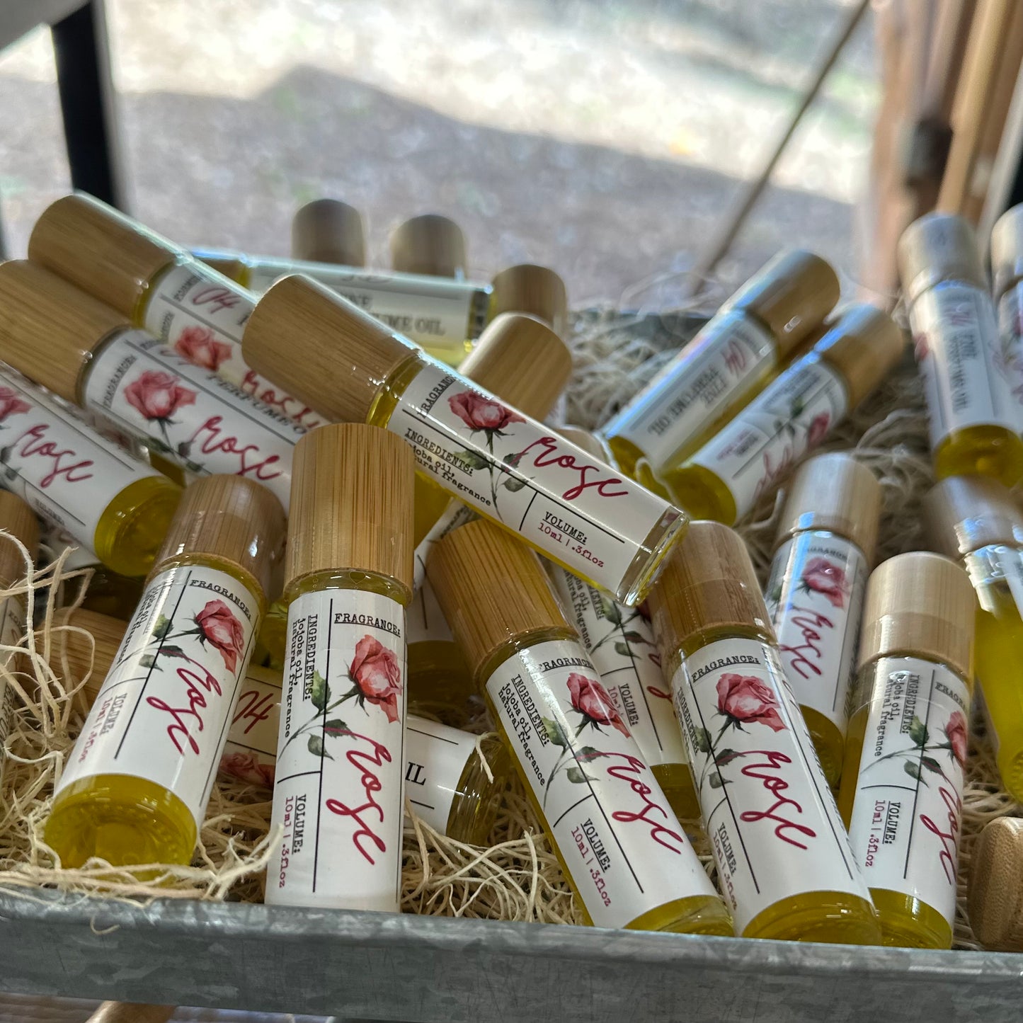 Roll-on bottles with rose designs and text on a woven surface.