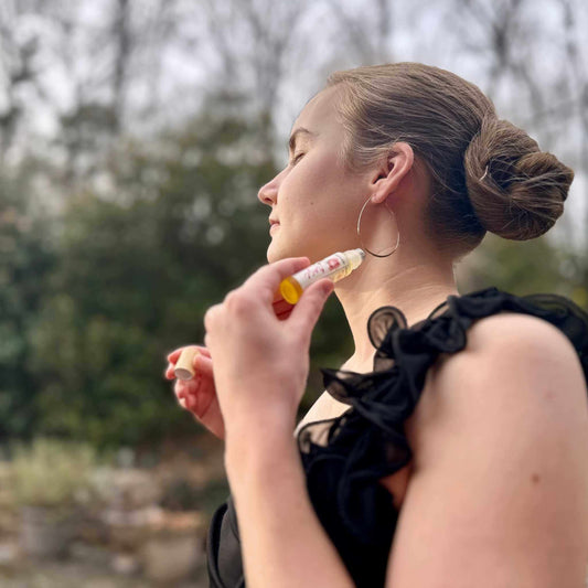 Woman applying perfume outdoors with trees in the background