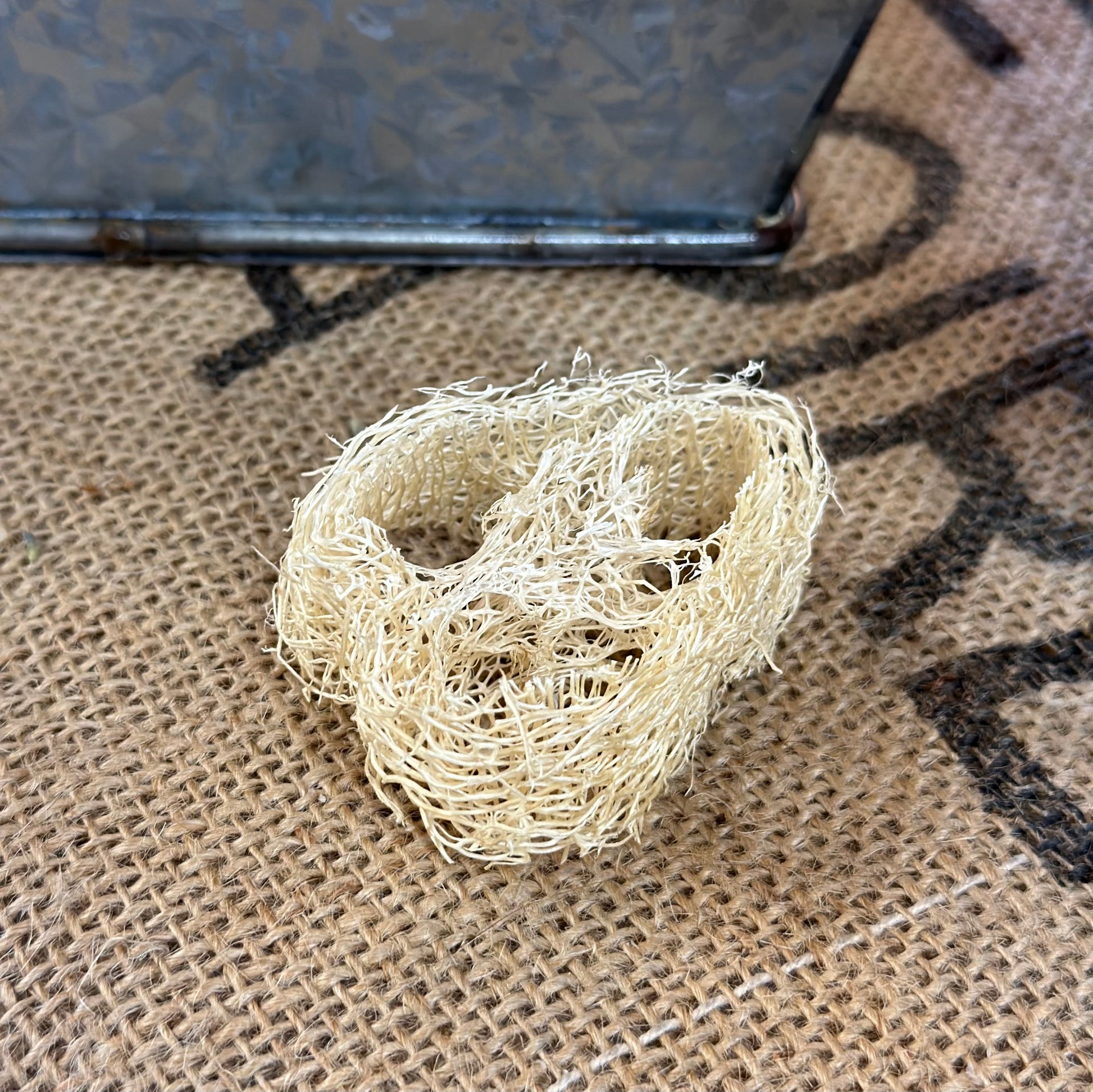 A natural beige loofah sponge on a textured background.